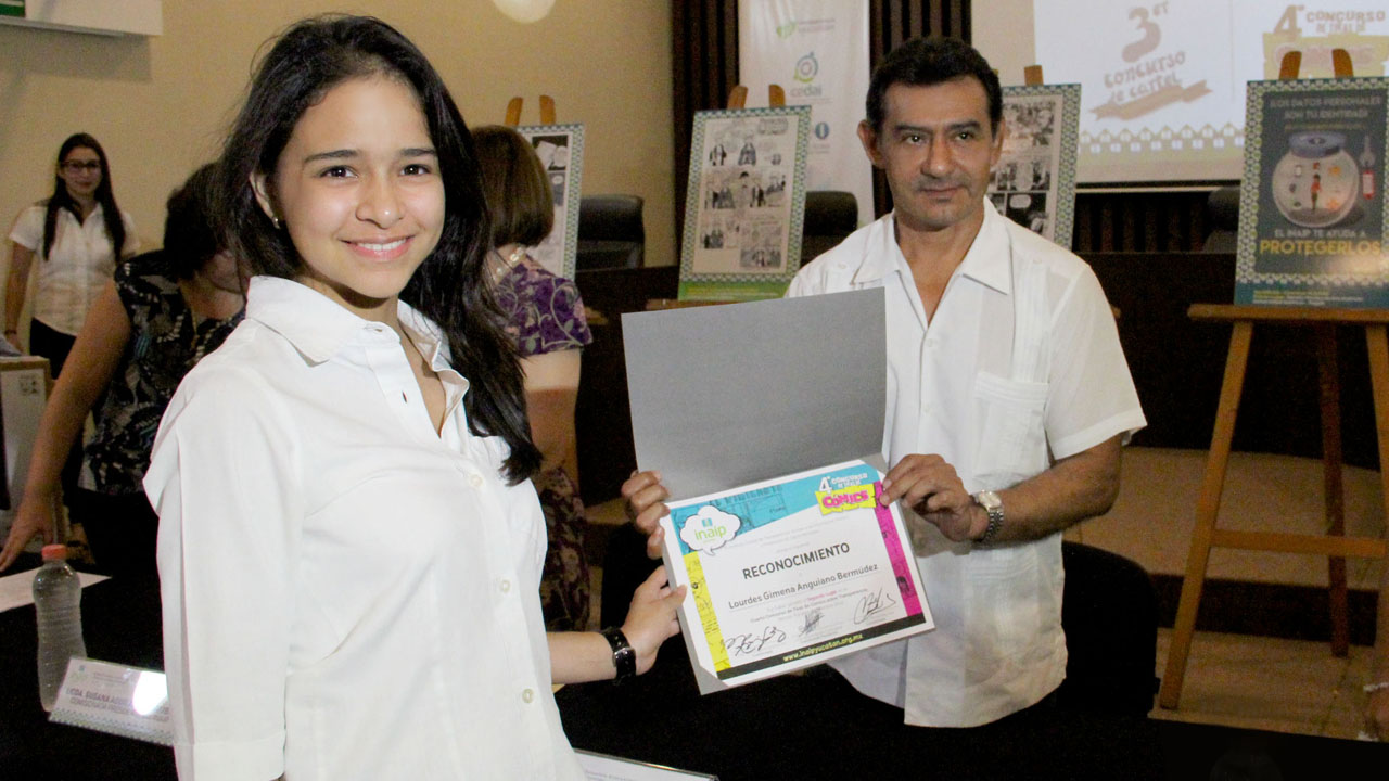 Lourdes Anguiano recibe por parte del comisionado Víctor May un reconocimiento por haber obtenido el 2° lugar del concurso de tiras de cómics