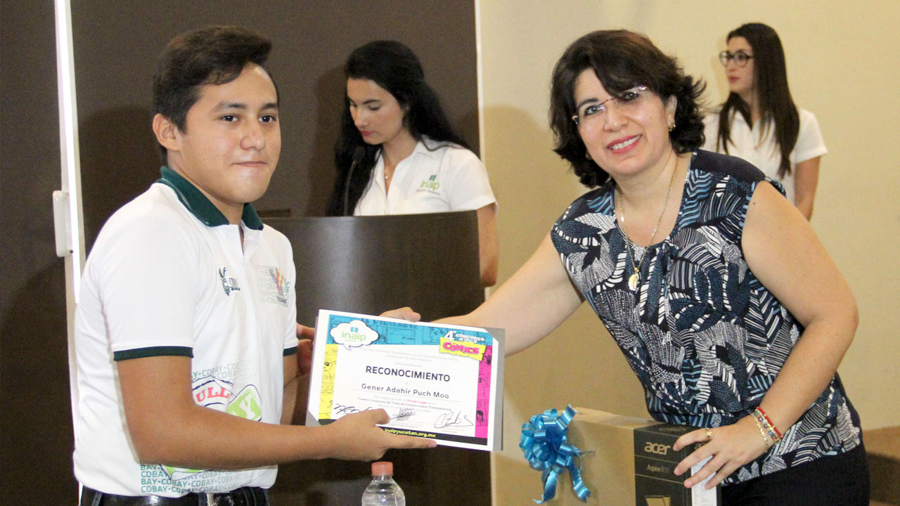 Gener Adahir Puch Moo, del COBAY Chenkú, recibie su premio de manos de la Comisionada María Eugenia Sansores Ruz, por ser el ganador del 1° lugar del concurso de tiras de cómic